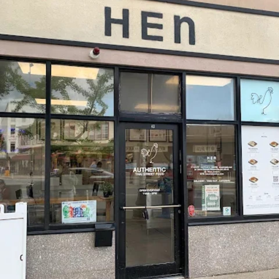 Exterior of Hen Thai restaurant with large windows, a glass door, and a sign above.