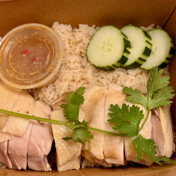 Thai Hen's Khao Man Gai with sliced chicken, rice, cucumbers, cilantro, and dipping sauce.