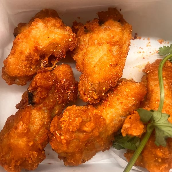 Crispy golden-brown Thai fried chicken wings seasoned with spices and garnished with cilantro.